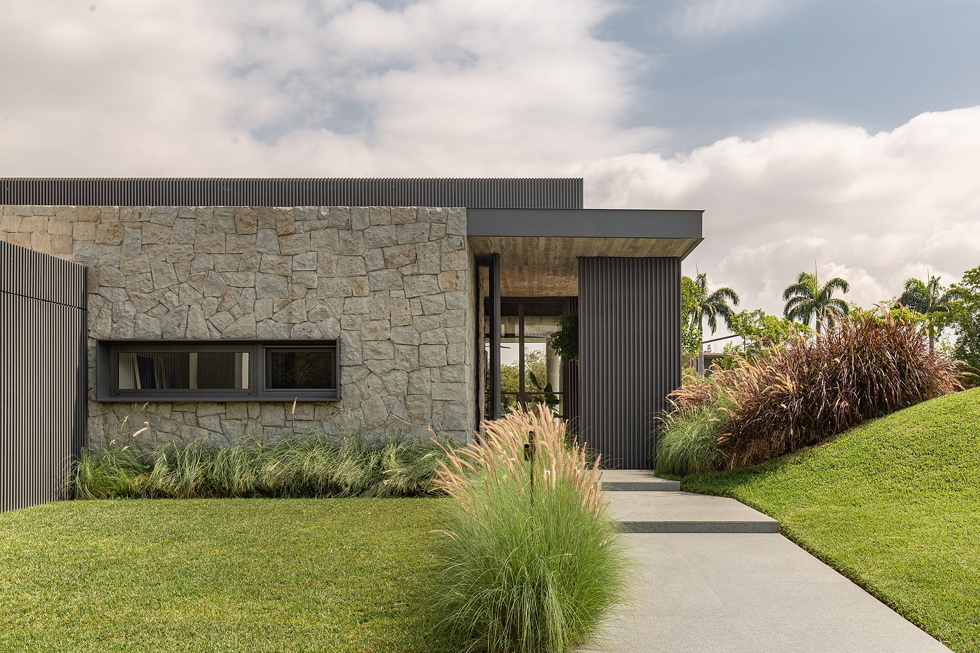 Fachada con jardines de una casa moderna de piedra