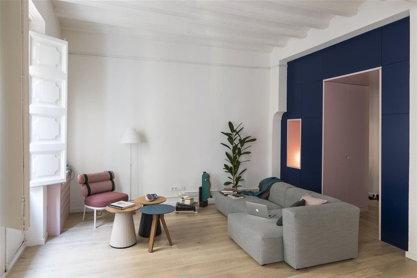 piso en barcelona con paredes de color rosa salon con sofa de color gris y ventana con molduras