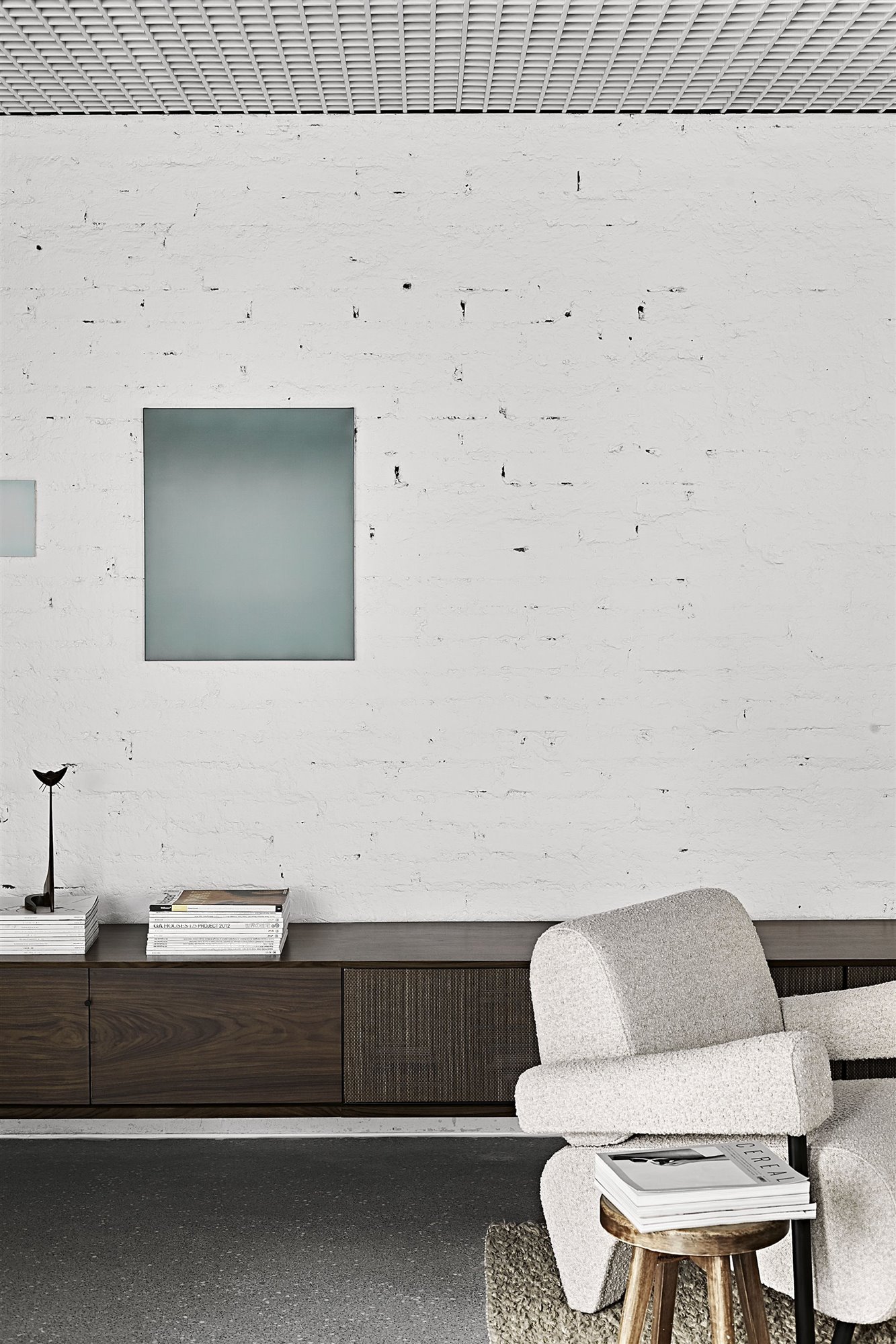 Salon con pared de ladrillo pintada de color blanco y butaca blanca copia
