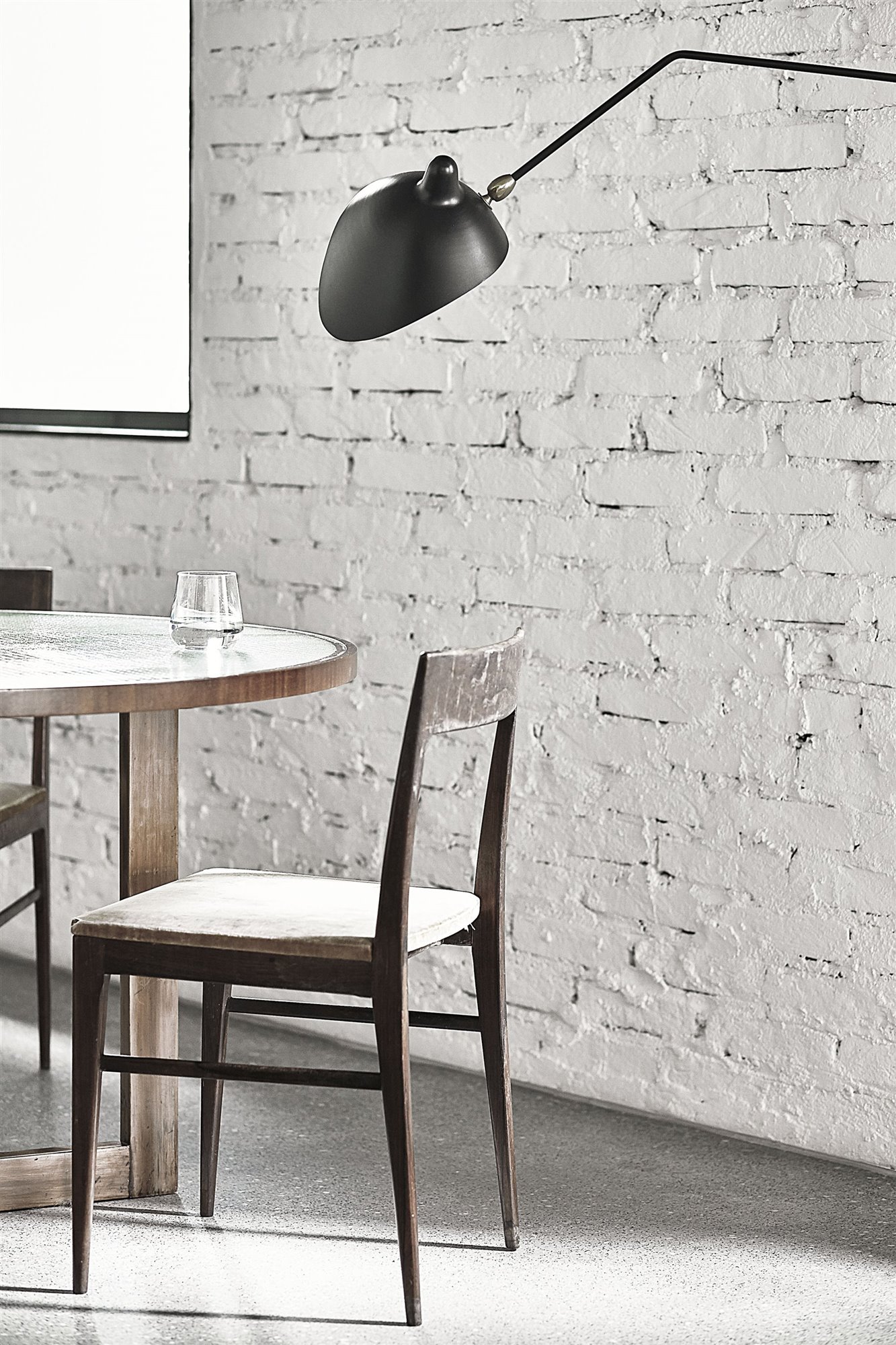 Silla de comedor con lampara negra tipo flexo y paredes de ladrillo copia