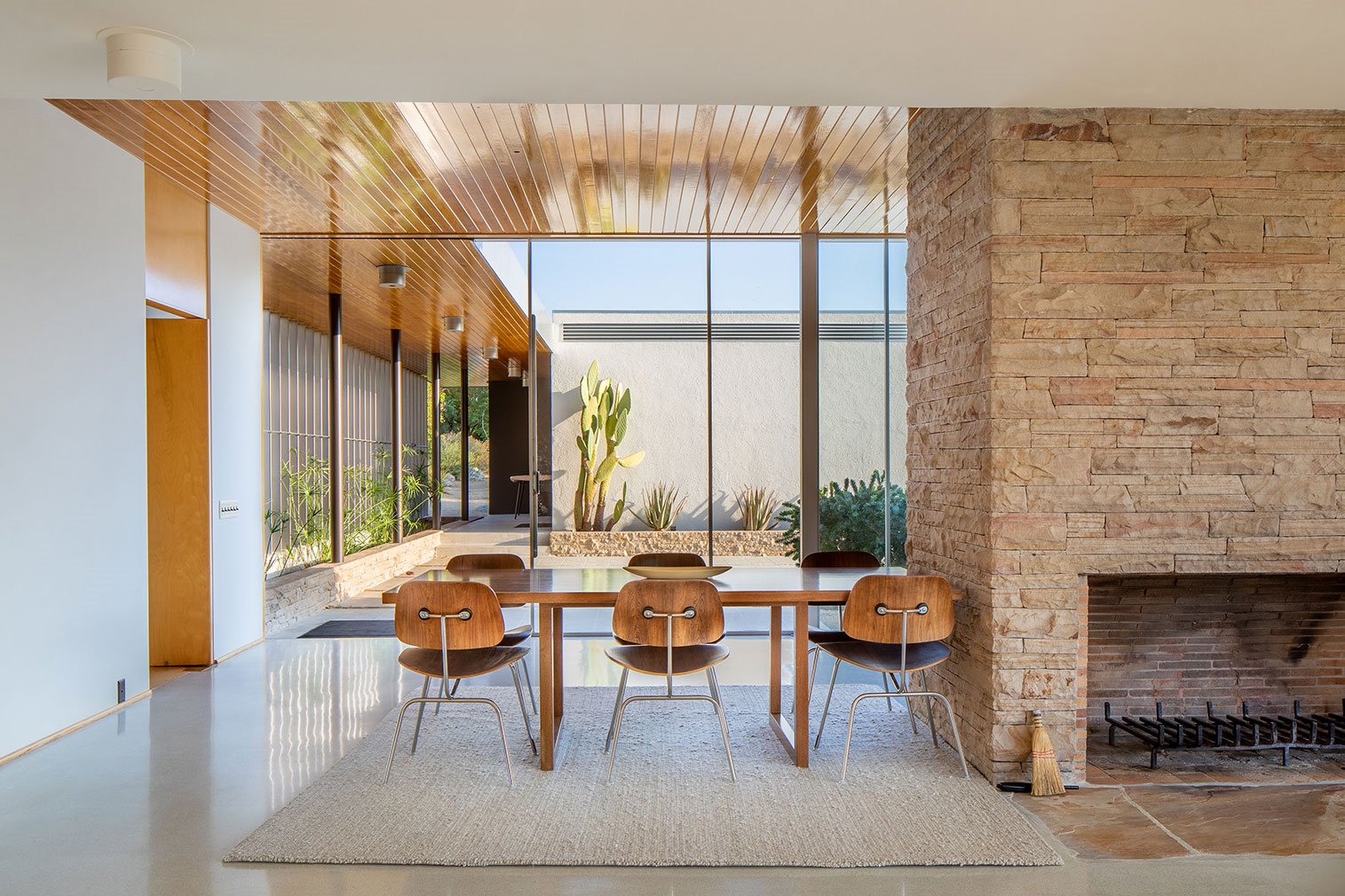 Casa Kaufmann de Richard Neutra en Palm Springs paredes de piedra y comedor con sillas de madera