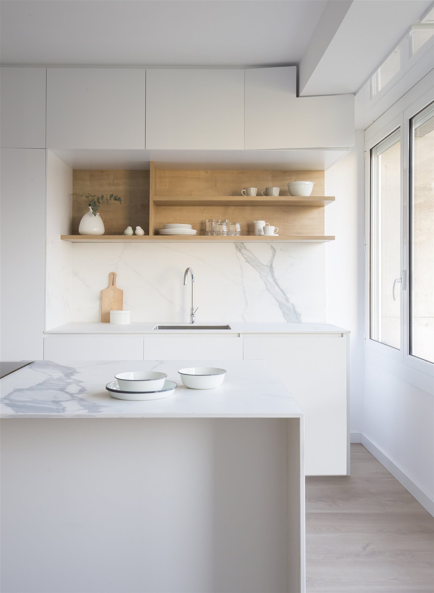 Cocina con frontal de marmol y muebles de color blanco y madera