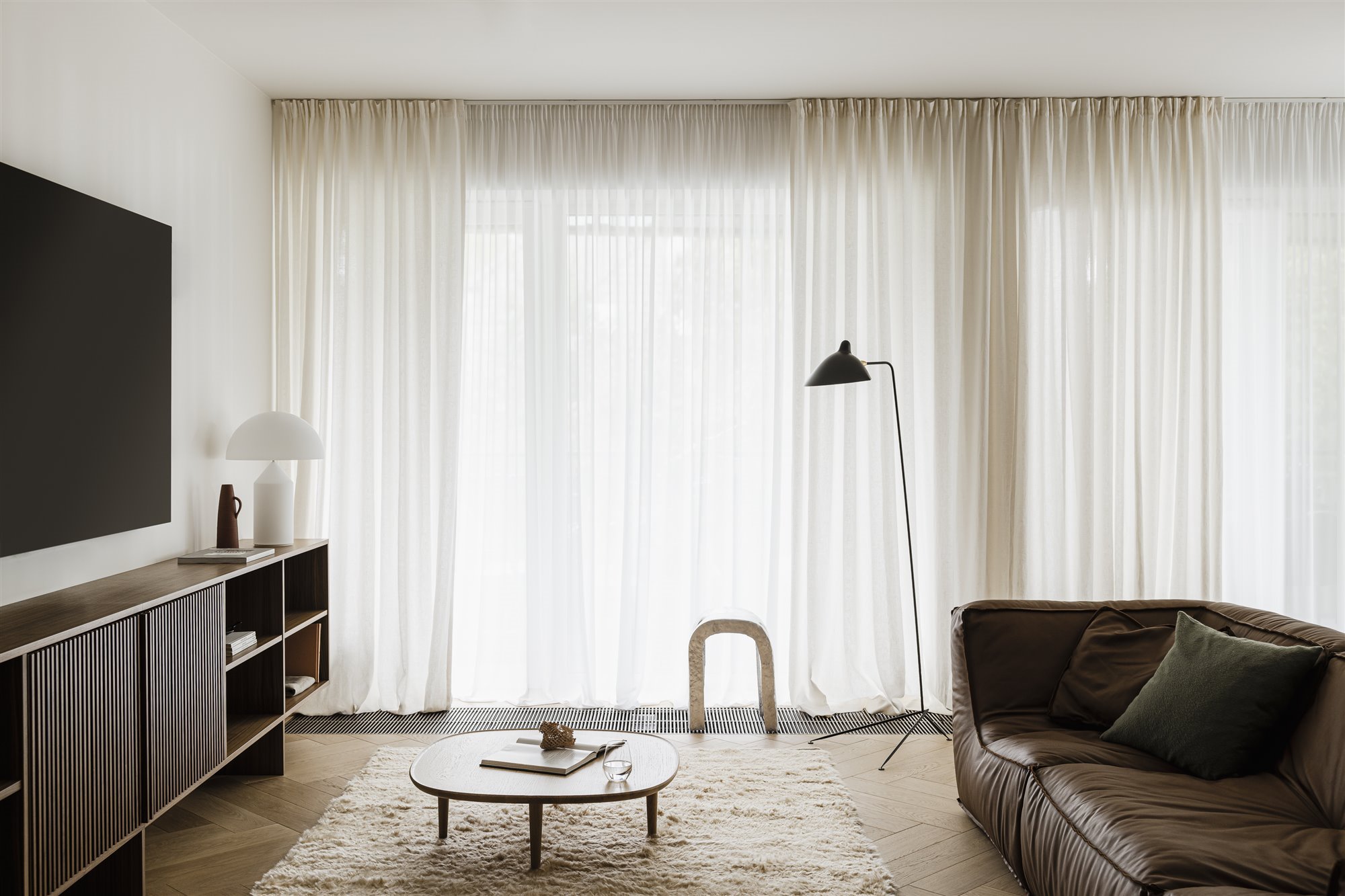 salon con sofa de piel y cortinas blancas
