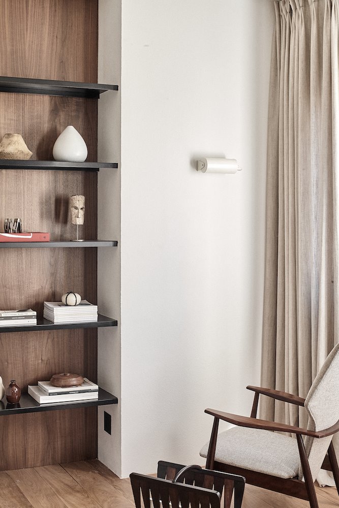 Piso con rincón con estanteria de obra negra y cortinas blancas