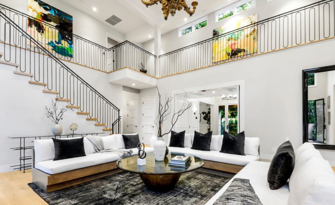 Salon con escalera doble altura sofas blancos casa cameron diaz