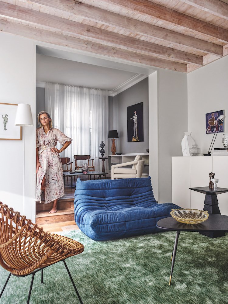 Salon con sofa de color azul y moqueta verde techo con vigas de madera