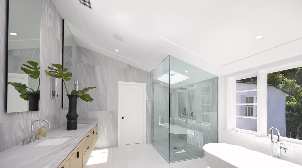 Baño en buhardilla con mampara de ducha y bañera de la casa de Justin Bieber y Hailey Baldwin