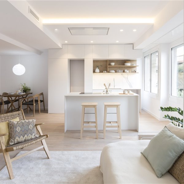 salon con cocina en isla y dos taburetes de madera
