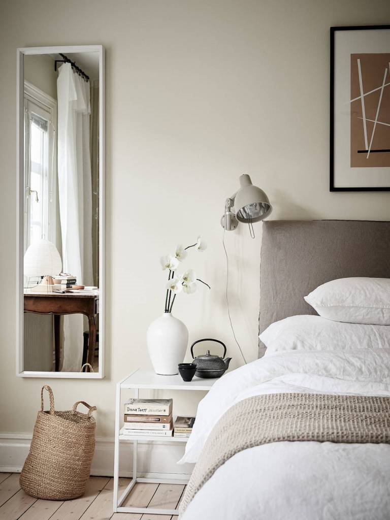 Domitorio con cabecero en color gris beige y pared en color ocre. Colores neutros