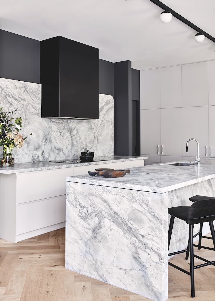 Cocina con taburetes de color negro y encimera de piedra gris