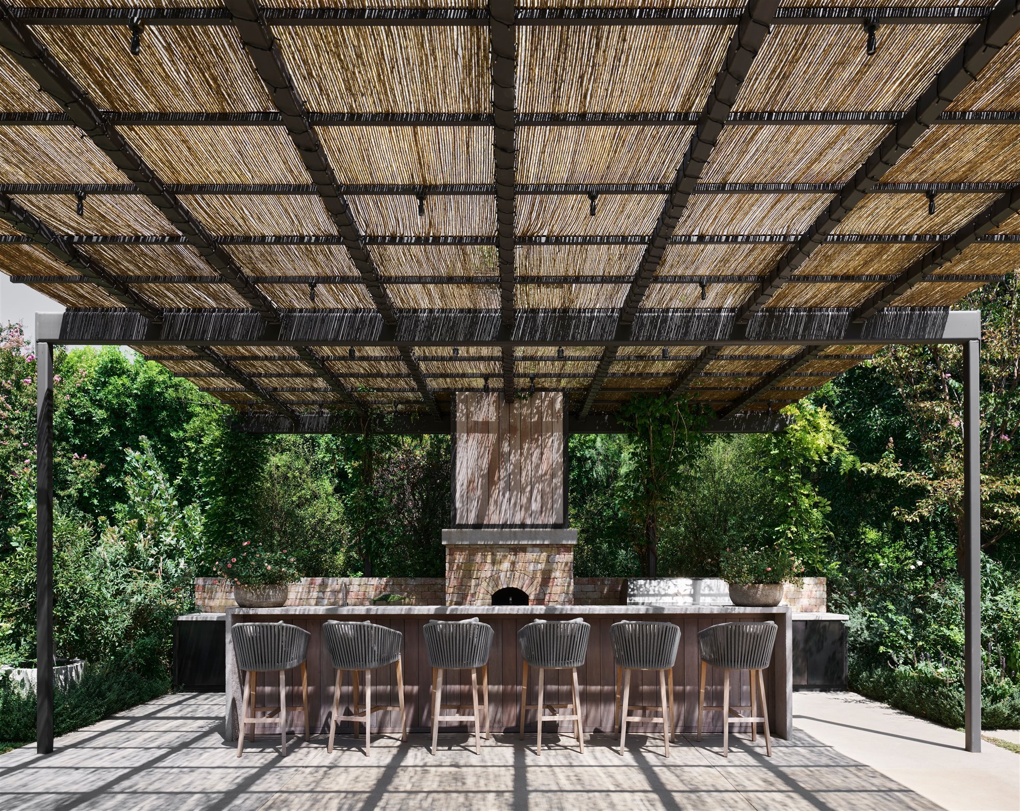Comedor exterior bajo una pergola de fibras naturales de la casa Kourtney Kardashian en Calabasas