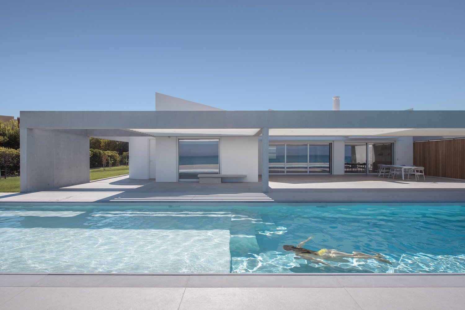 Casa con fachada blanca y piscina en mitad del campo