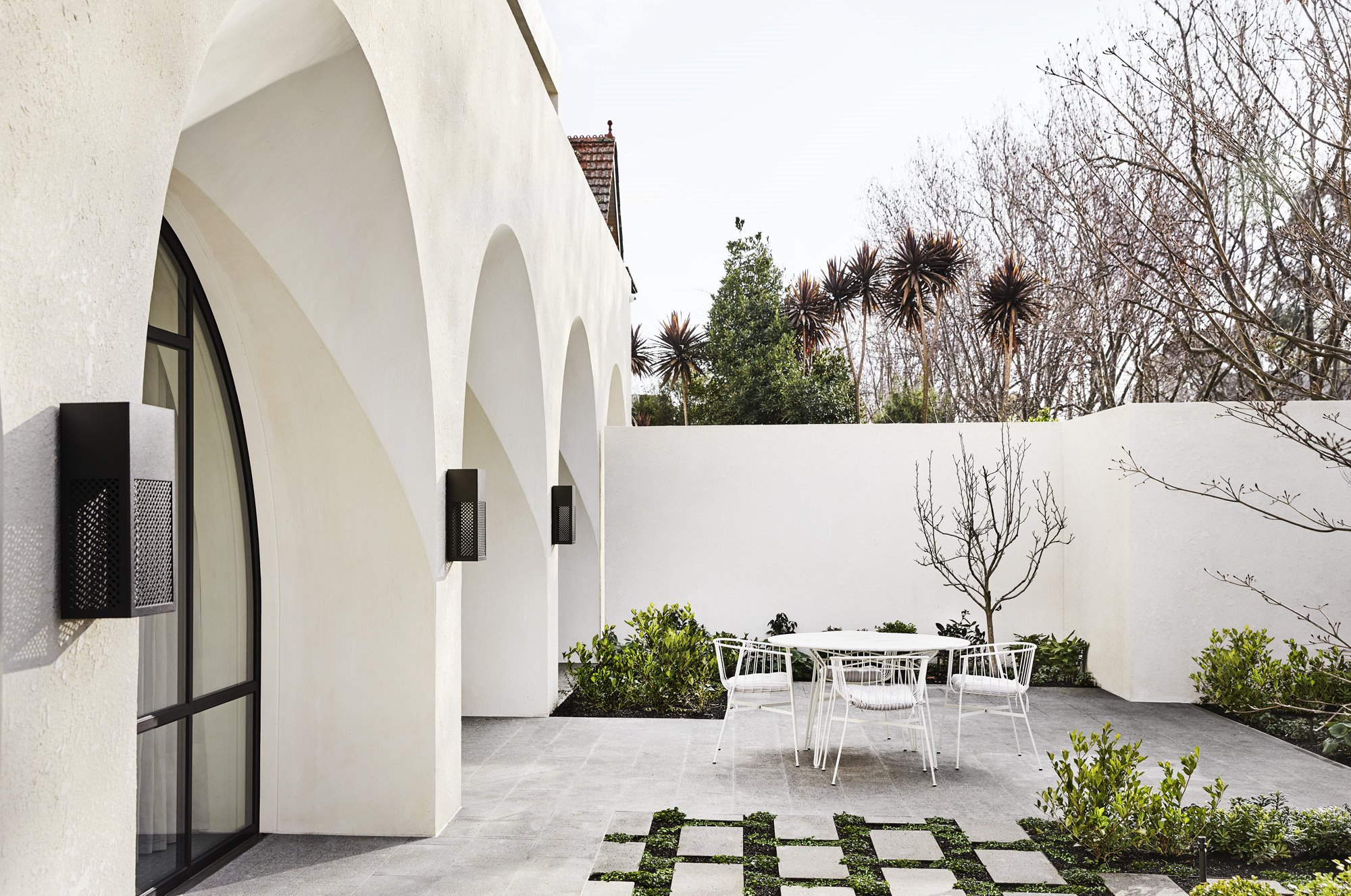 Entrada con patio exterior con sillas y mesa de color blanco