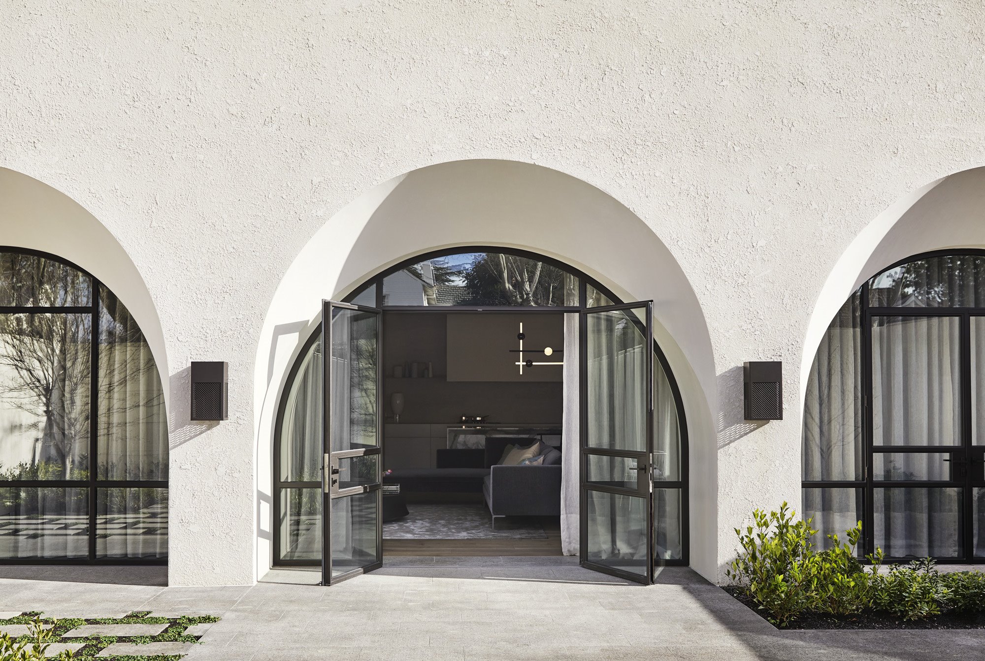 Entrada de una casa con fachada blanca y puertas de cristal