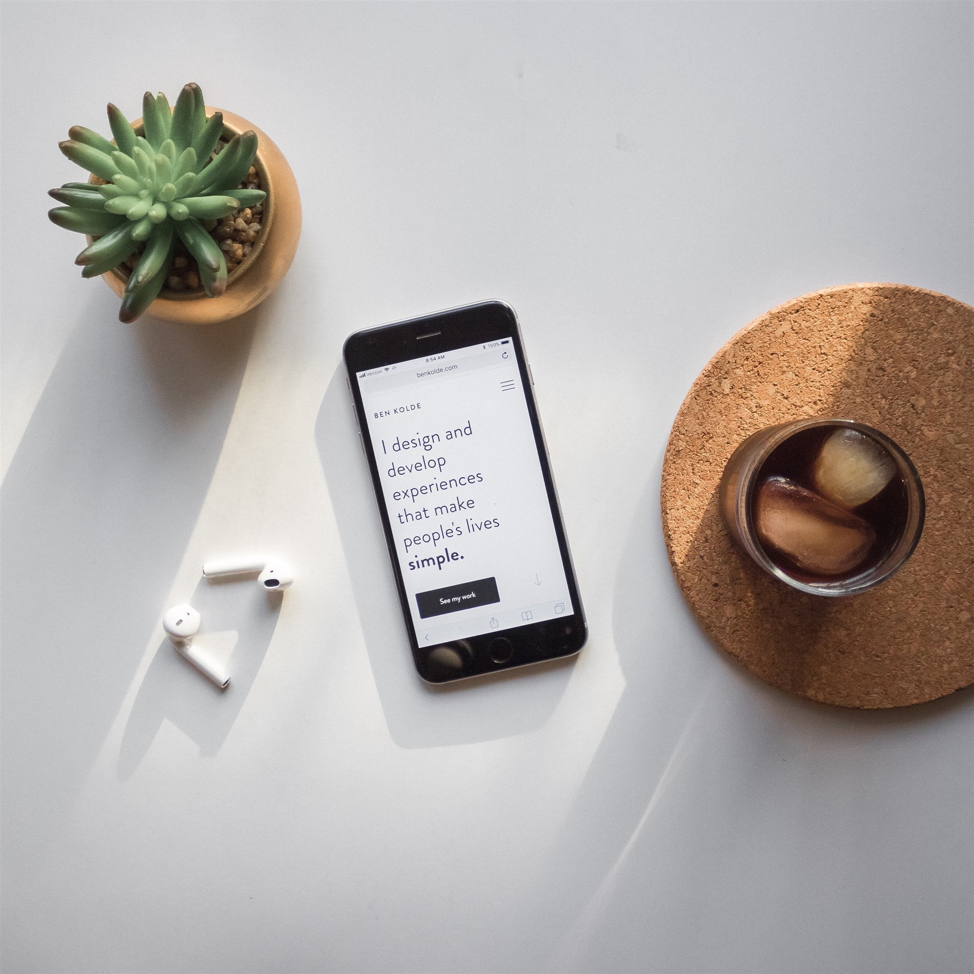 Telefono movil con auriculares y plantas sobre una mesa blanca