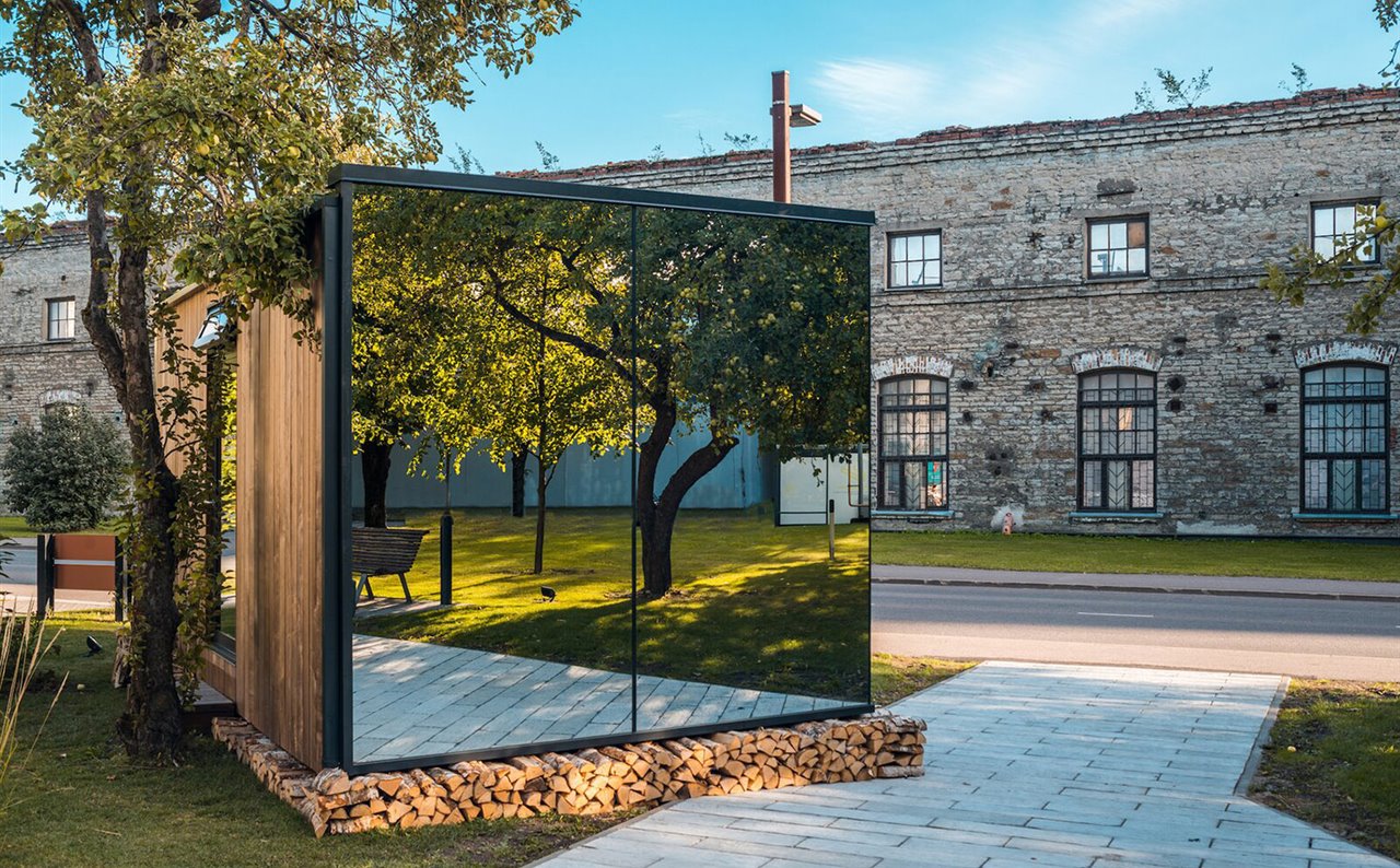 La construcción combina una estructura de madera con fachadas revestidas con cristal reflectante que la integran en el entorno.