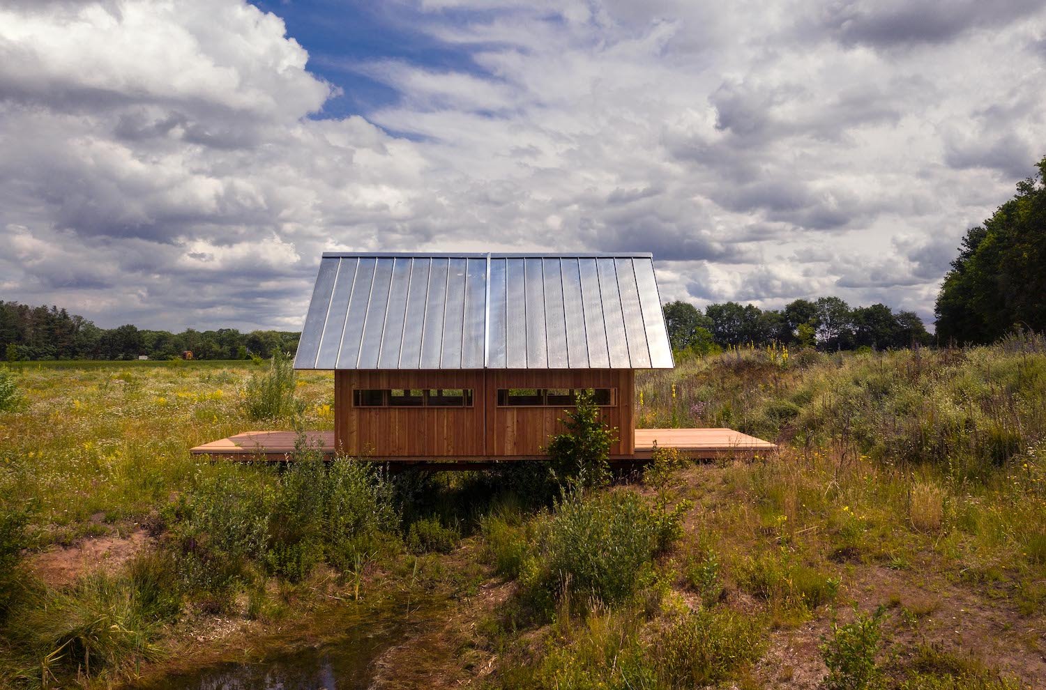 Cabaña de madera plegada con techo de aluminio en mitad del campo