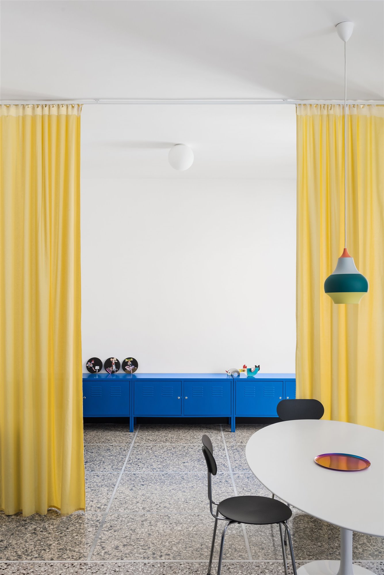 Comedor con cortinas de color amarillo y mueble de color azul de un piso en milan
