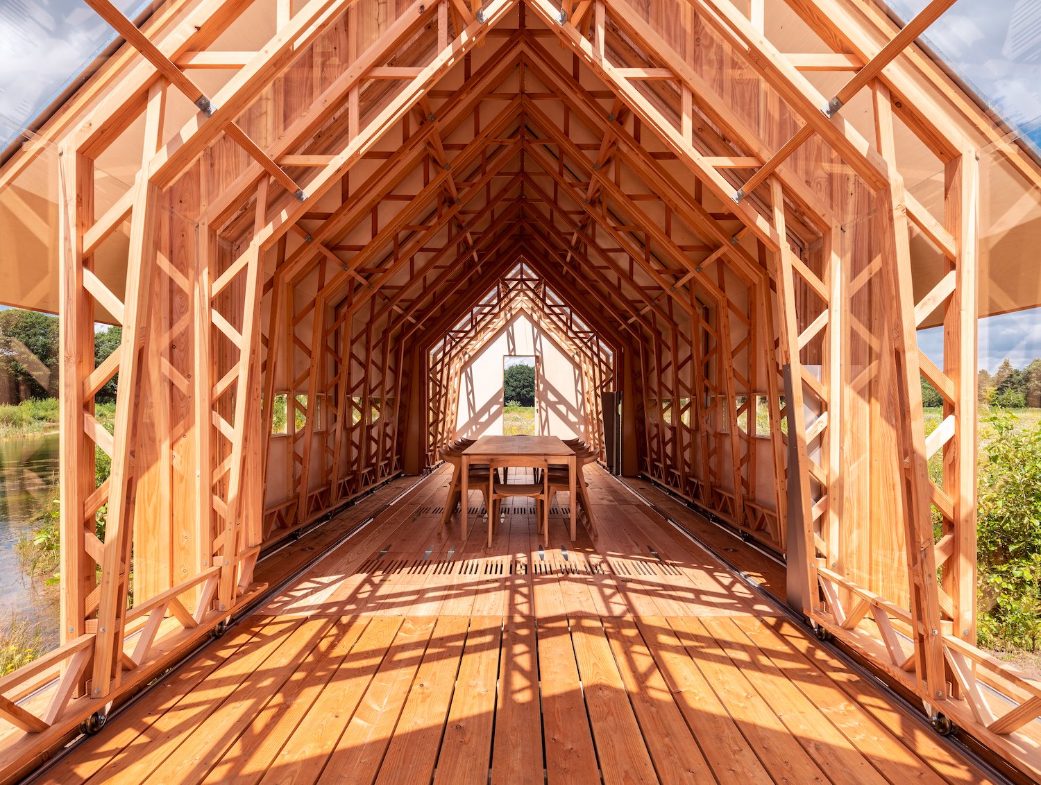 Comedor de una cabaña de madera con suelo de lamas en mitad del campo