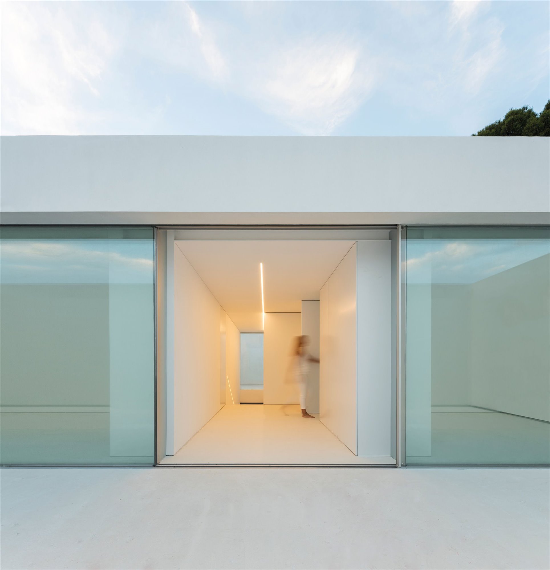 Entrada de una casa moderna con paredes de cristal y fachada blanca