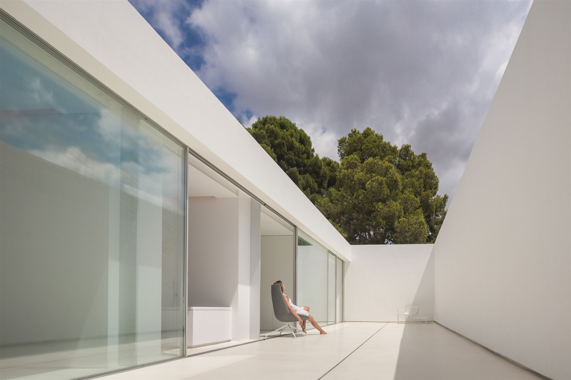 Patio interior de color blanco de uan casa moderna con mujer sentada