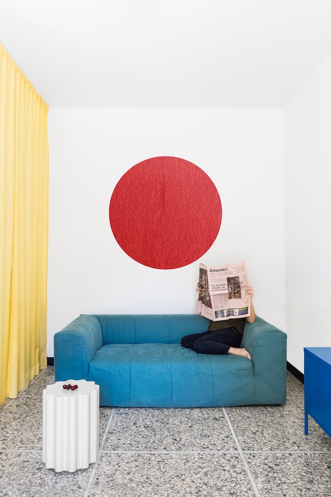 Salon con sofa y cuadro redondo de color rojo de un piso en milan