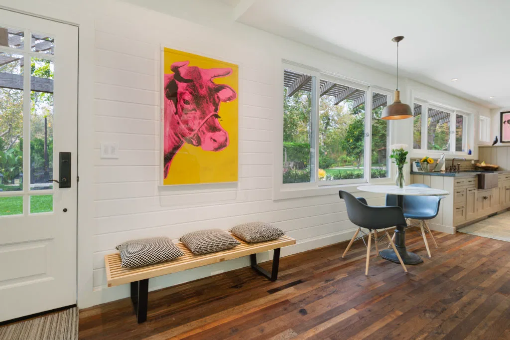Entrada con banco de madera y mesa redonda con dos sillas de plastico de la la casa de Reese Witherspon