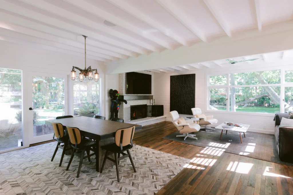Salon con sillas de madera y butacas eames blancas de la casa de Reese Witherspon