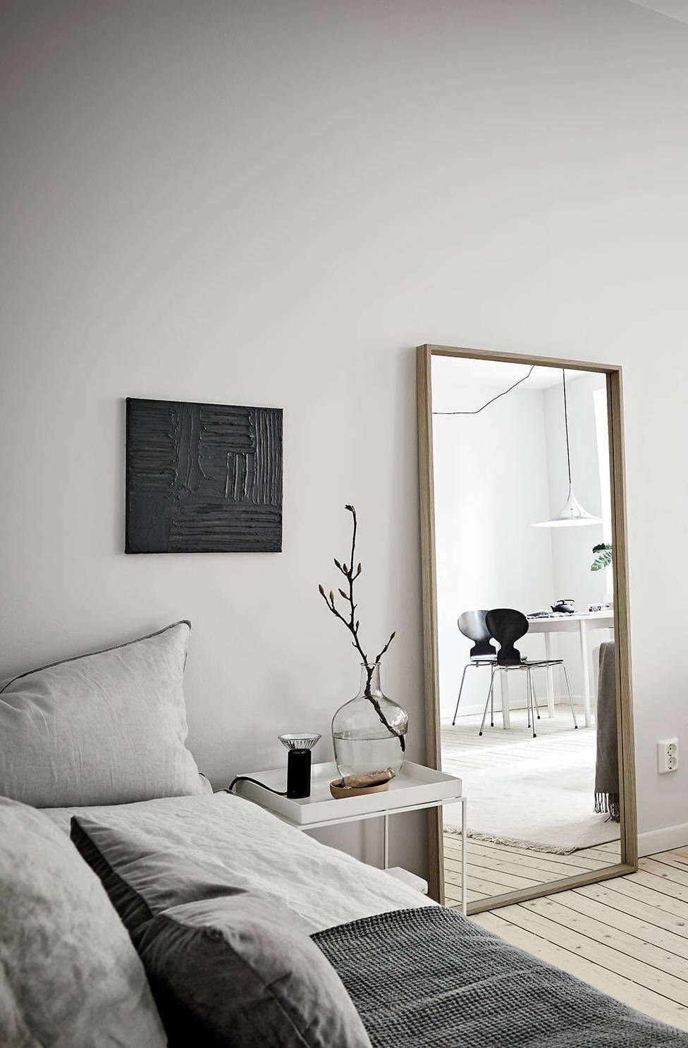 Salon son sofa gris suelo de tablones de madera y espejo apoyado en la pared