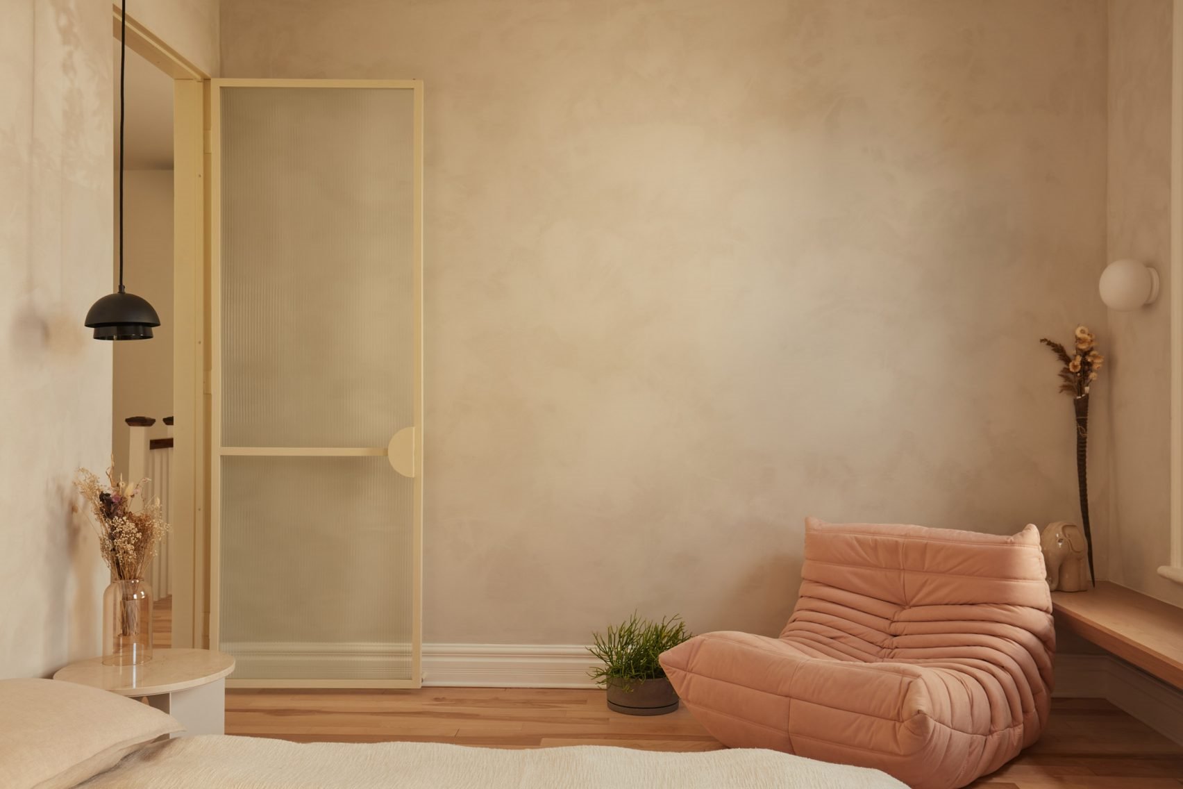 Dormitorio de un piso en Montreal con sofa Togo en rosa y paredes de color ocre