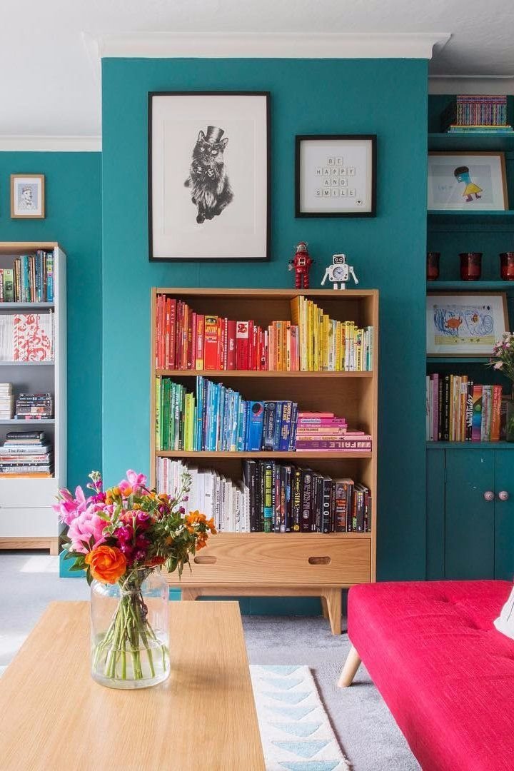 Estanteria en el salon con libros ordenados por colores. En estantes