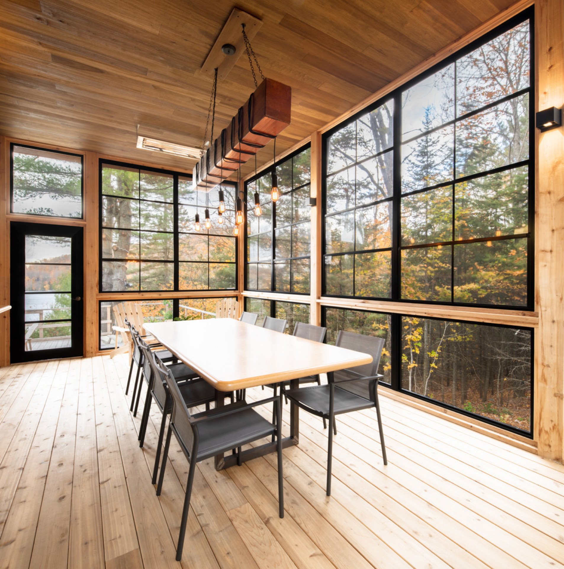 Comedor con ventanas de cristal y suelos de madera de una casa en Canadá