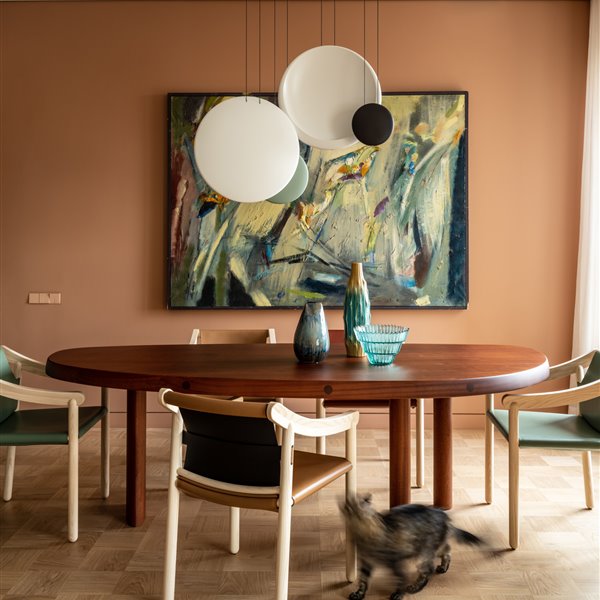 Comedor con paredes de color rojizo mesa redonda y sillas de madera de un piso en Moscu reformado por Agnes Rudzite
