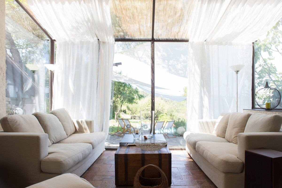 Casa con salon con cortinas blancas abierto a la naturaleza. Cerca de Barcelona