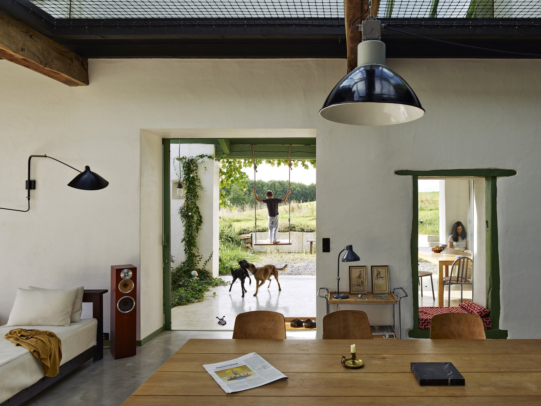 Antiguo establo abandonado convertido en casa moderna en Francia comedor con vistas al exterior perros jugando