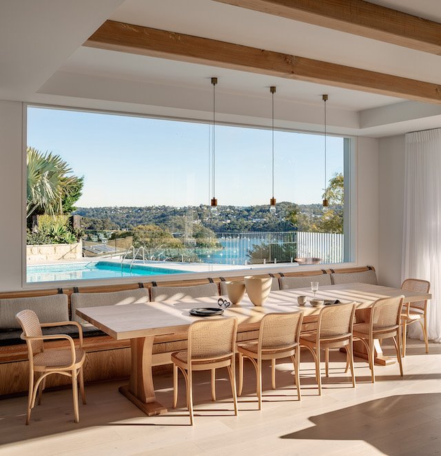 Comedor con mesa de madera y banco de obra con vistas a la piscina