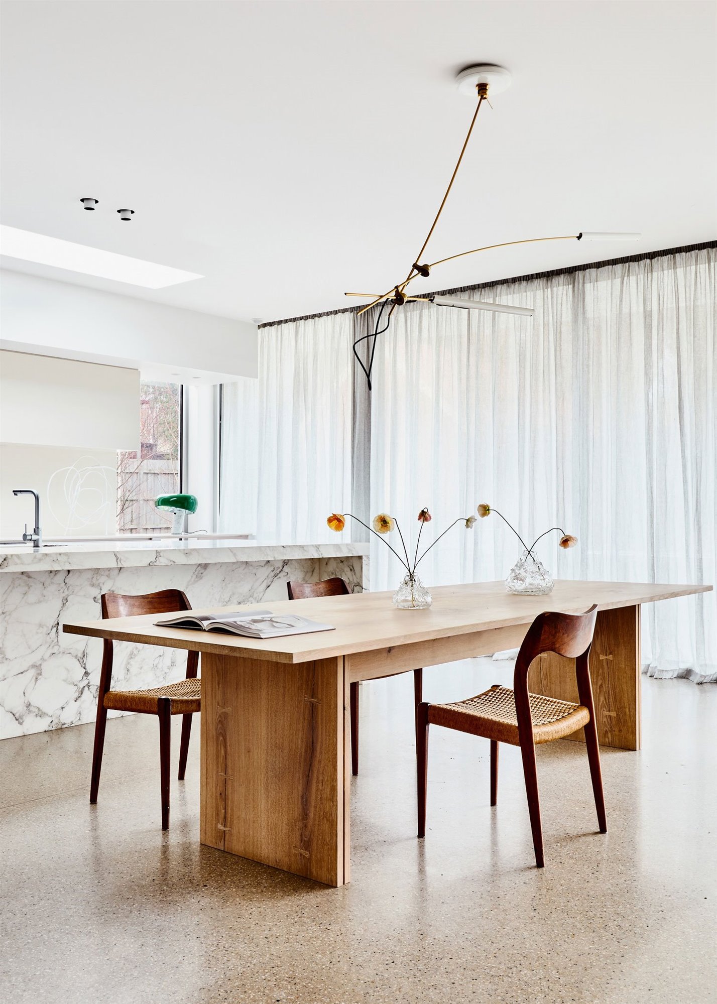 Comedor con mesa de madera y cortinas blancas de una casa en Australia