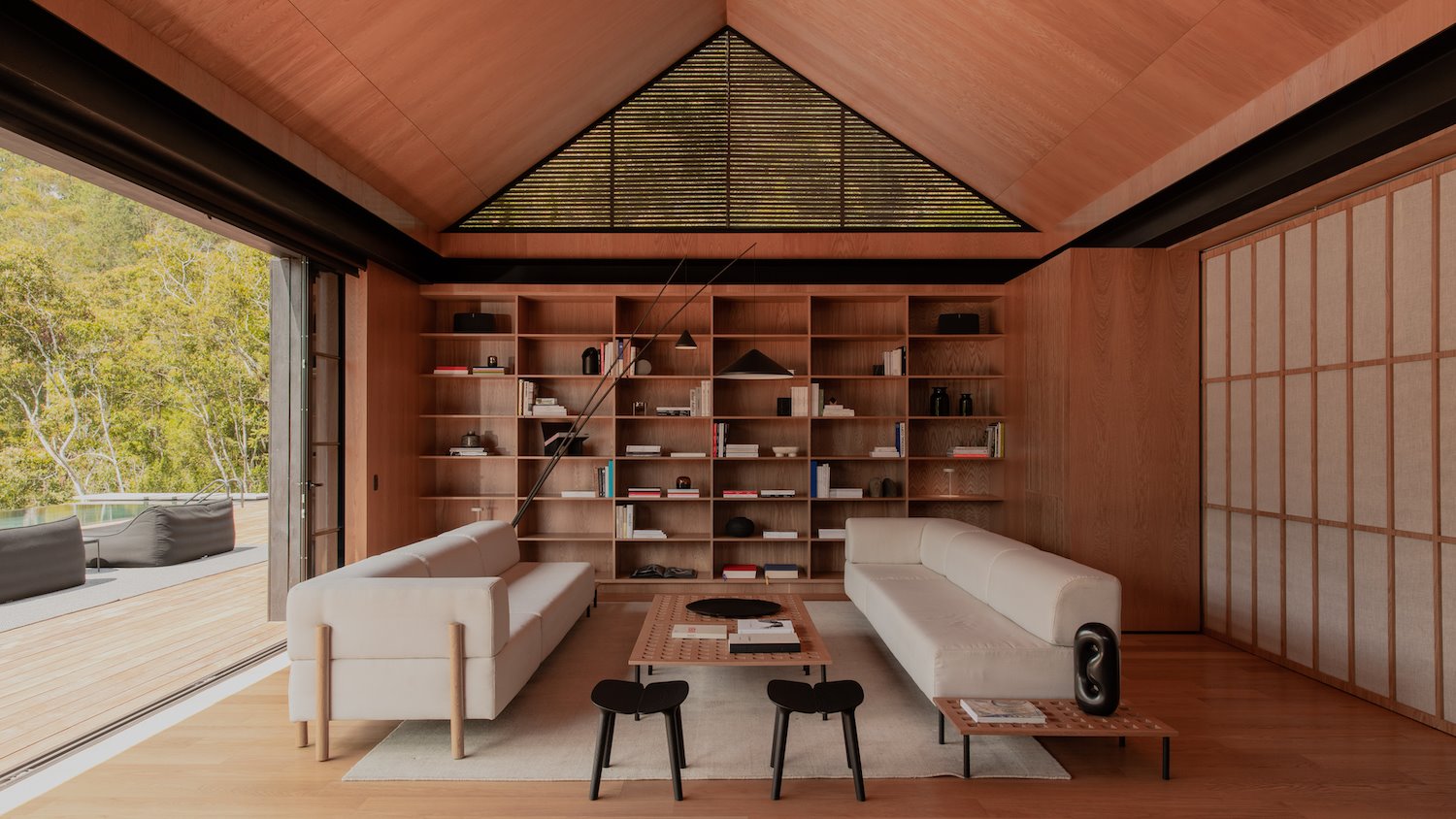 Salon con interiores de madera y sofas de color blanco de la casa del cantante J Balwin en Medellin