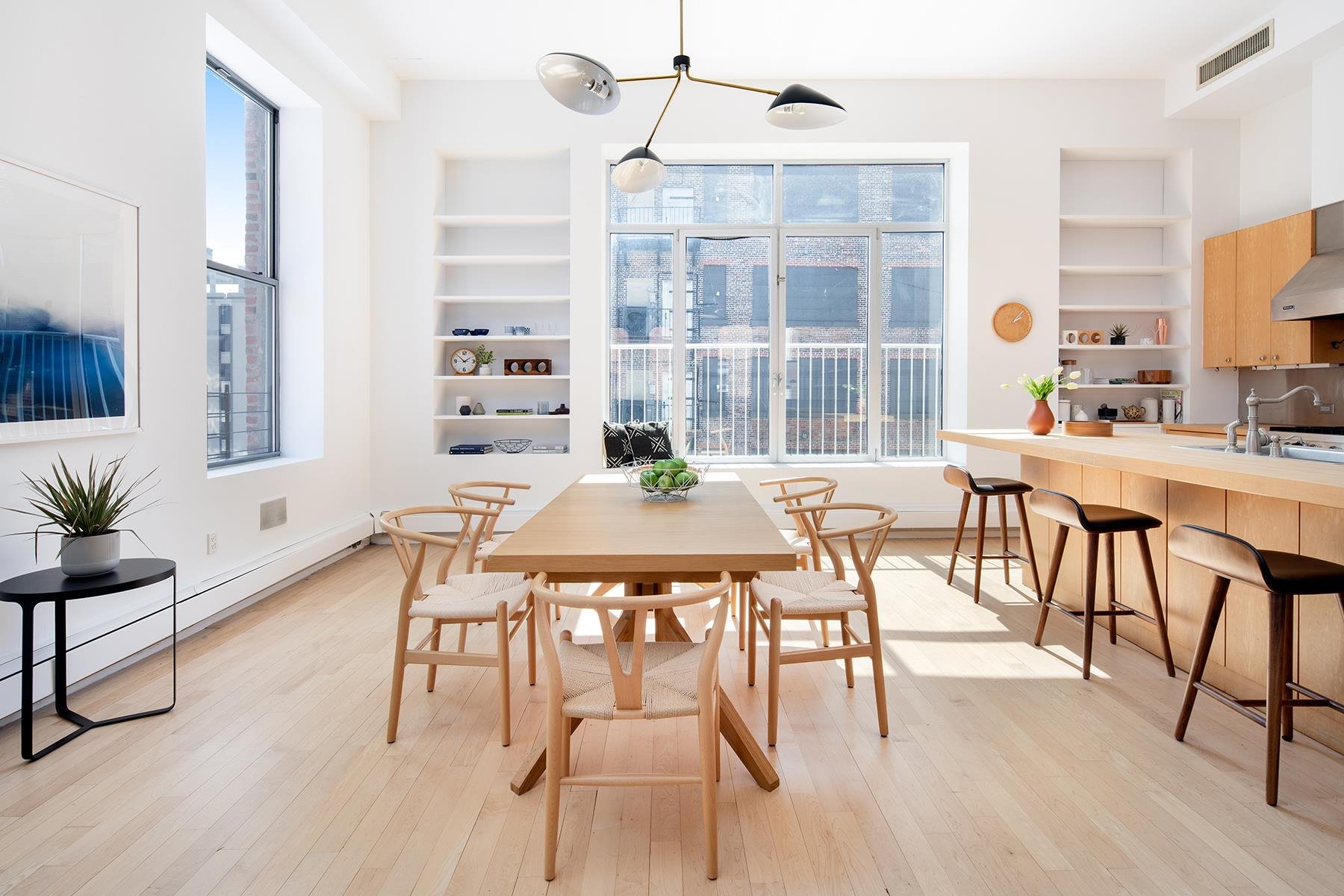 Comedor con sillas de madera y lampara de color negro del apartamento atico de Kate Winslet en Nueva York