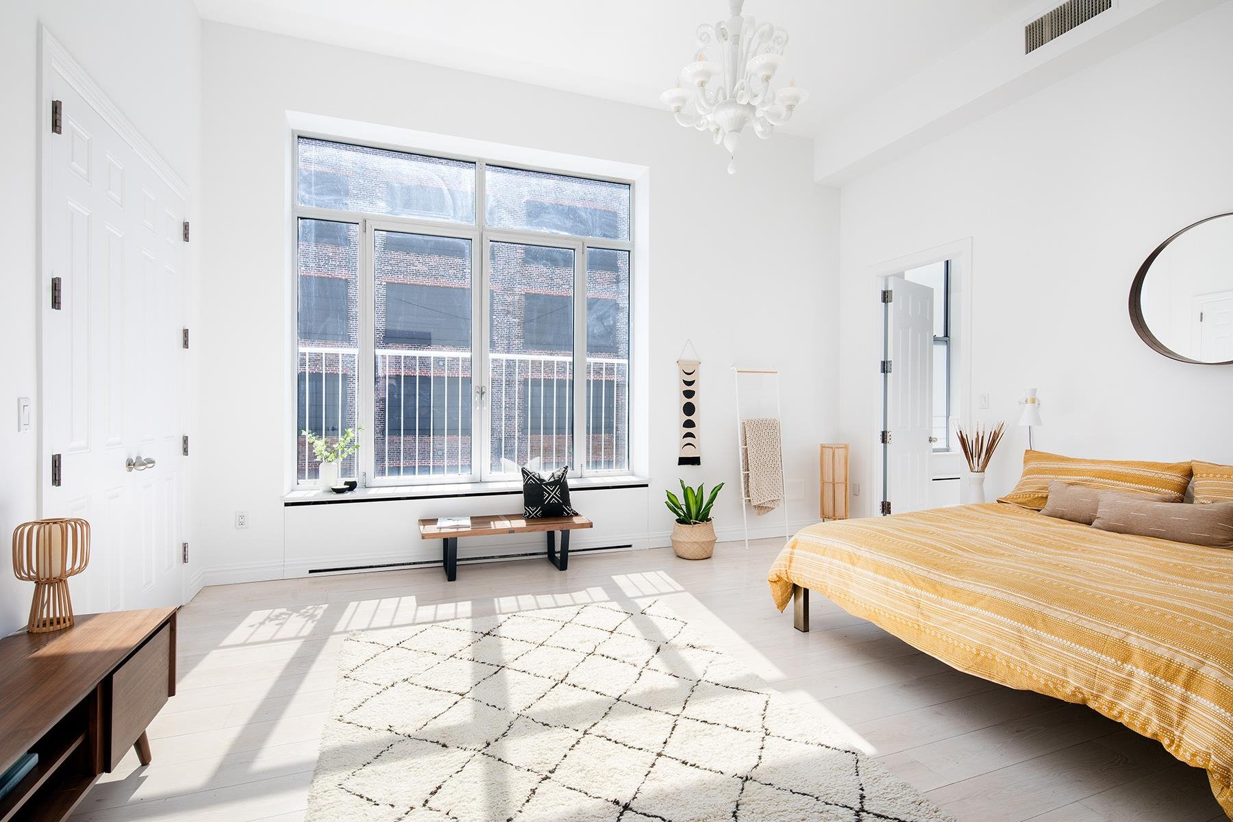 Dormitorio con cama de color amarillo y espejo redondo del apartamento atico de Kate Winslet en Nueva York