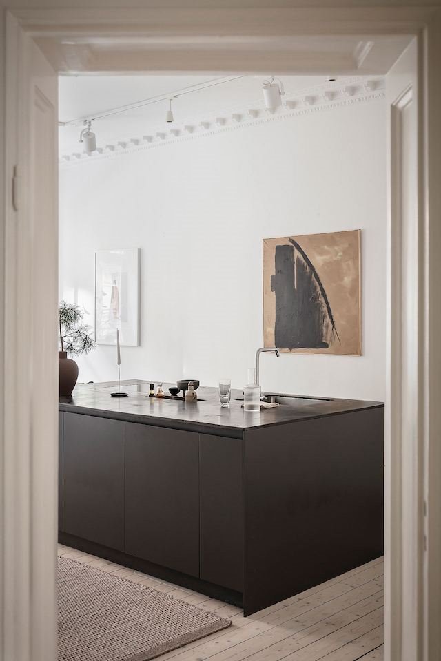 Apartamento en Estocolmo con cocina en isla de color negro y moduras en la pared