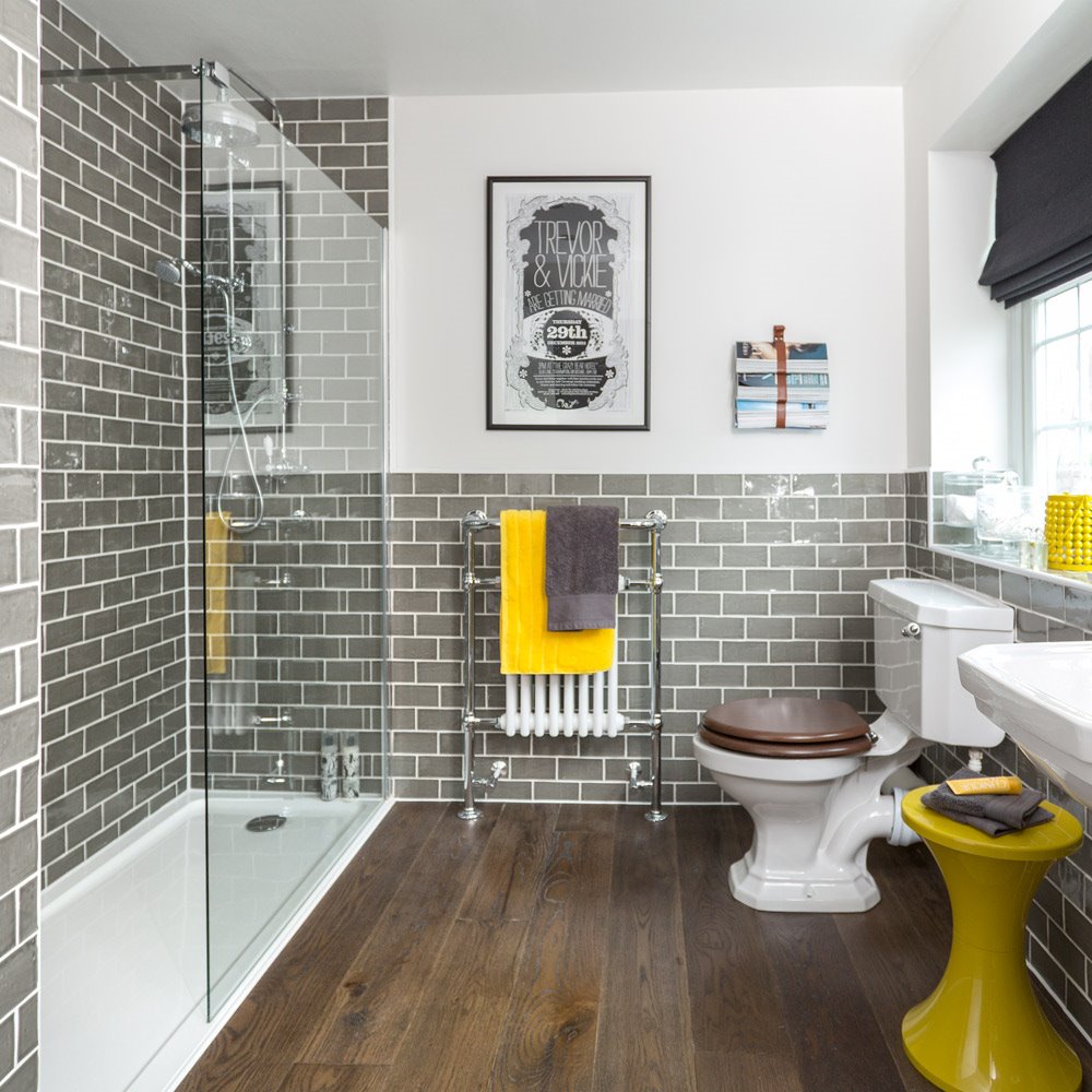 Baño con toallas de color amarillo y baldosas en color gris