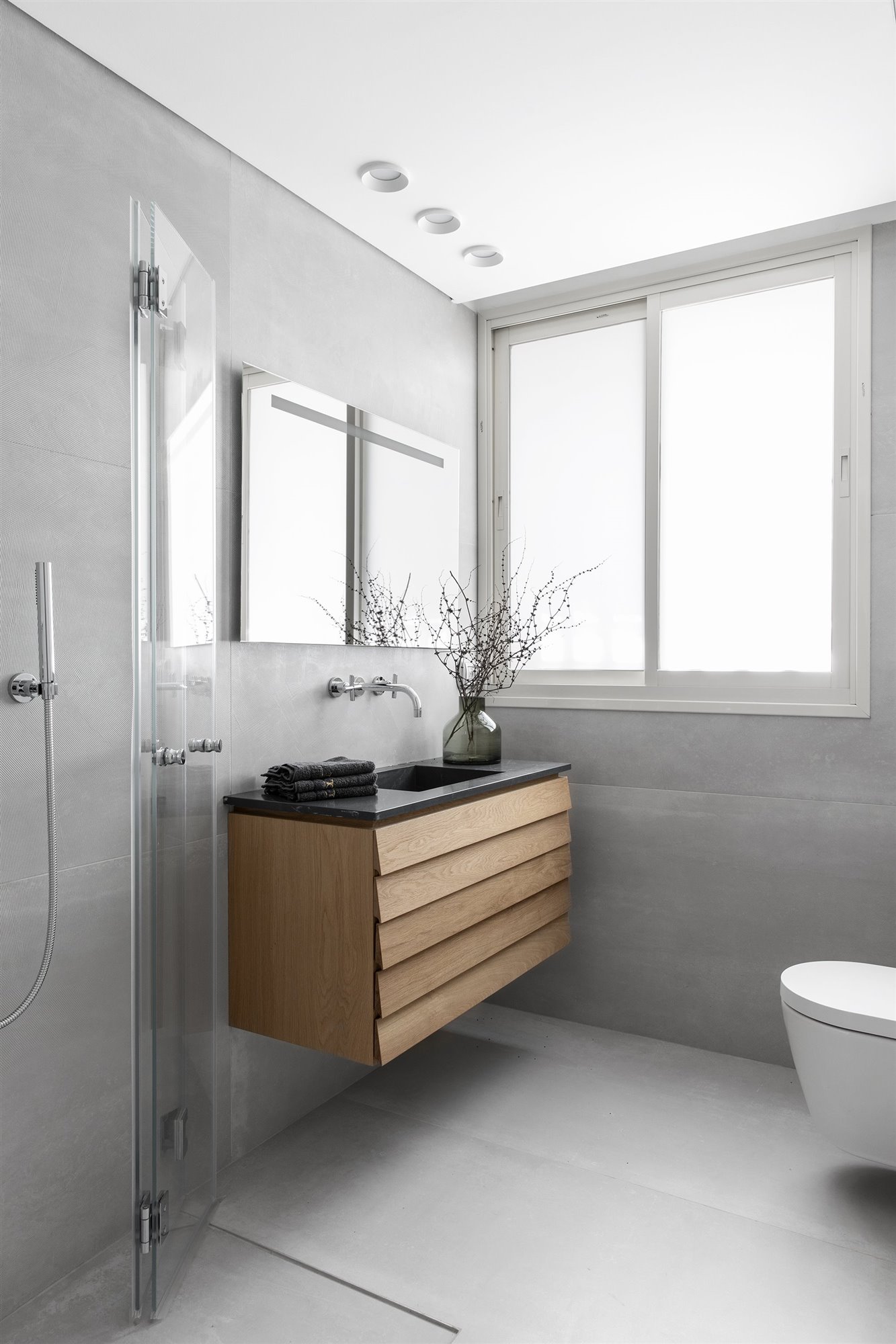 Baño con mueble suspendido de madera y acabados en color gris