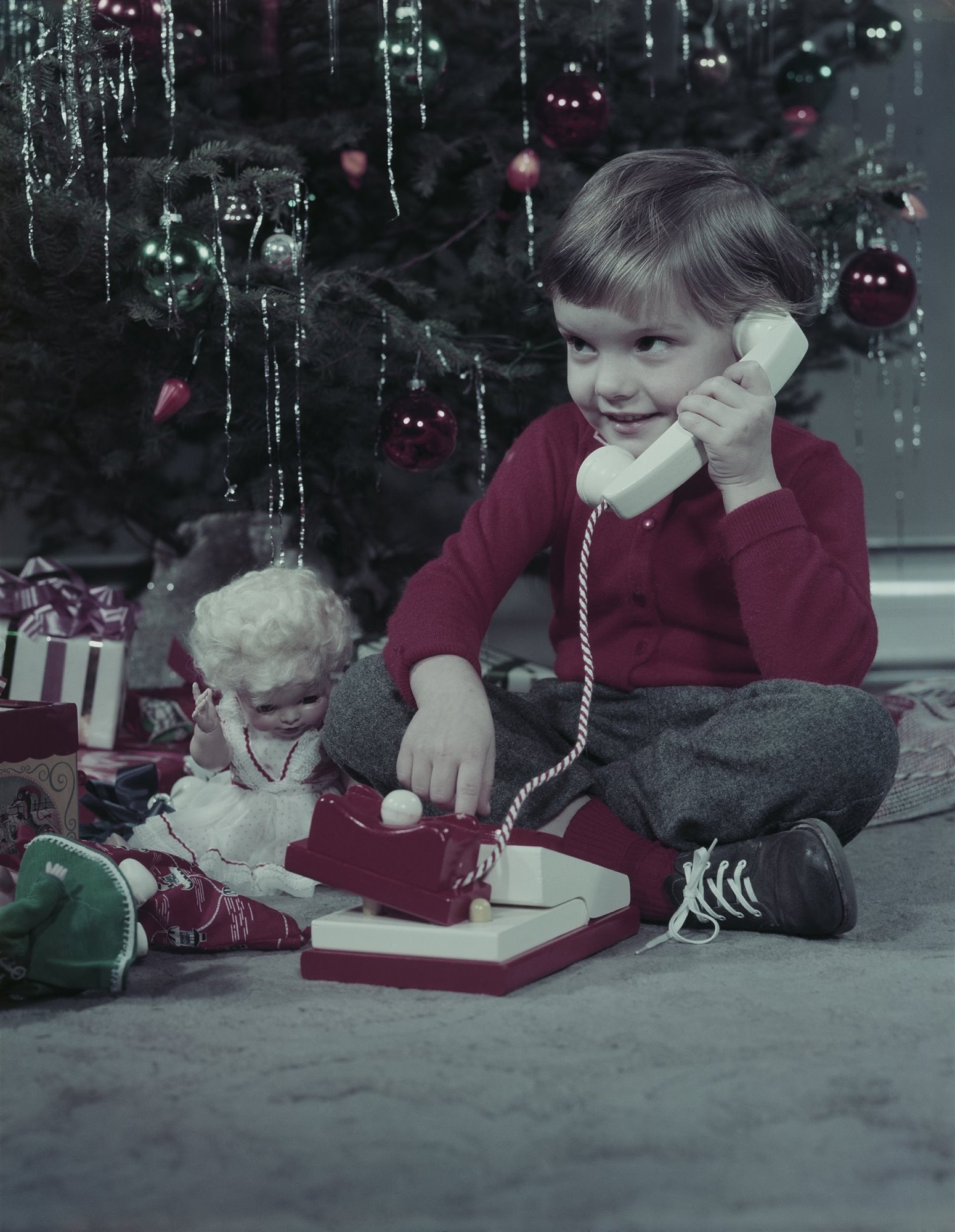 Niño jugando con un telefono en Navidad. 1952