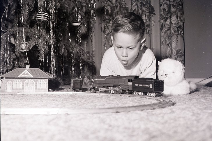 Niño jugando con un tren en navidad años cincuenta. 1959