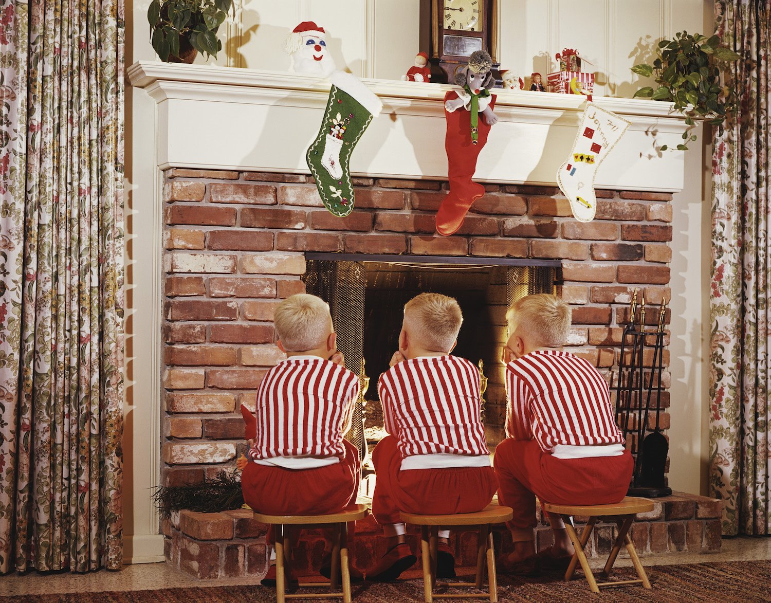 Niños frente a una chimenea en Navidad vestidos iguales. 1968