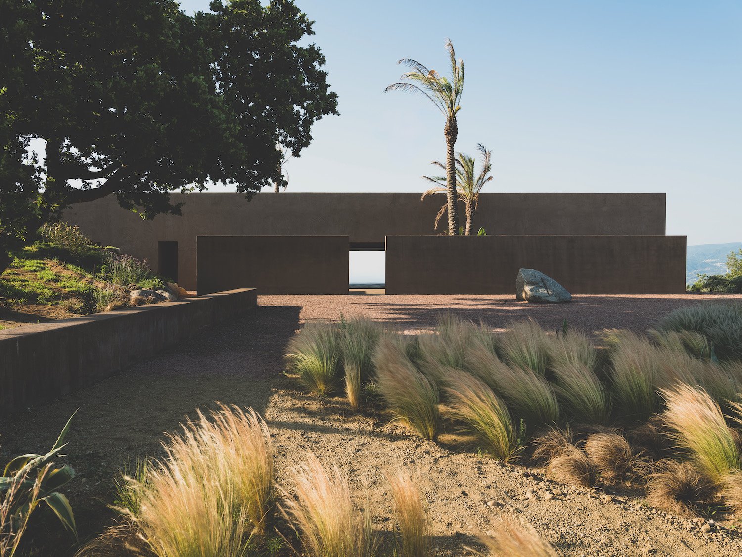 Exterior fachada de la villa Ra de Morq Architecture. Villa RA, cuya imagen exterior muestra una estructura compacta puntuada por proporcionadas aberturas que enmarcan el paisaje.