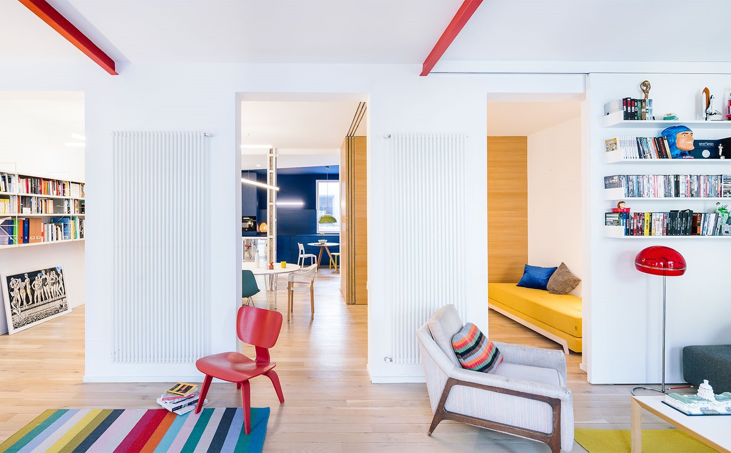 1.madrid.zona-de-salon-y-trabajo-con-amplias-aperturas-hacia-cocina-radiadores-verticales-en-pared-vigas-pintadas-en-rojo 881ab6f6 1500x930