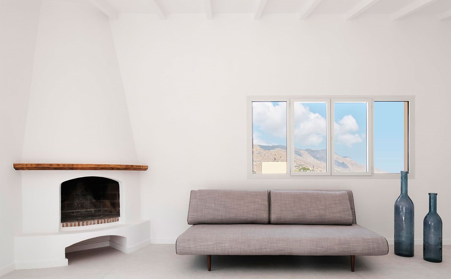 1.mallorca.chimenea-en-esquina-junto-a-sofa-en-gris-y-ventana c3f1ed70 1500x930. Esencia tradicional mallorquina