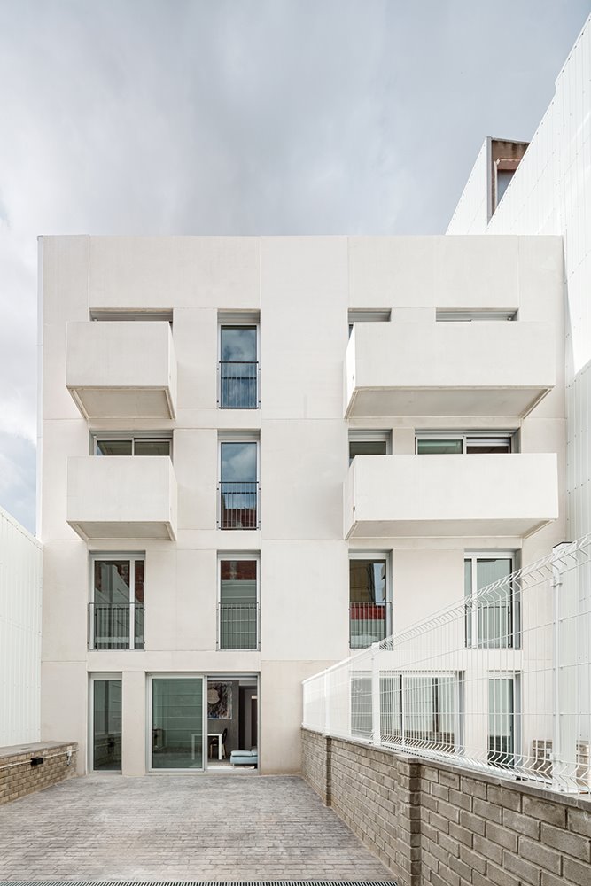 Las fachadas están formadas por paneles autoportantes de hormigón liso visto color blanco. En la fachada posterior, los balcones se han realizado con prelosa y panel arquitectónico prefabricado de hormigón.